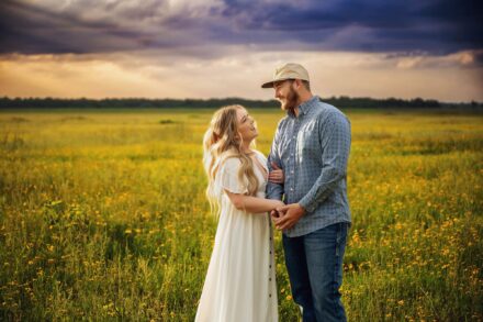 couple standing facing each other smiling in flower field