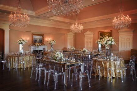 wedding reception room at the Oaks Club Osprey with clear ghost chairs, gold glitter table clothes, and chandeliers