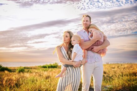 mom and dad holding little boy and girl standing in sea oats on beah