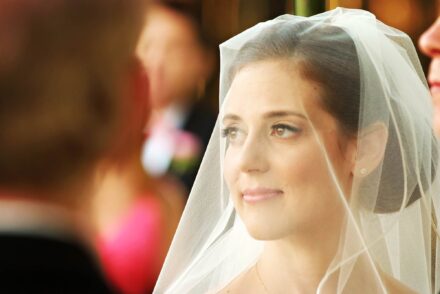headshot of bride during ceremony with veil over face and pleasant expression