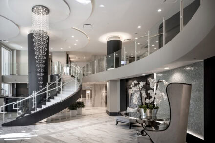 naples condo lobby with curved glass stair railing, chandelier, sitting area with orchid