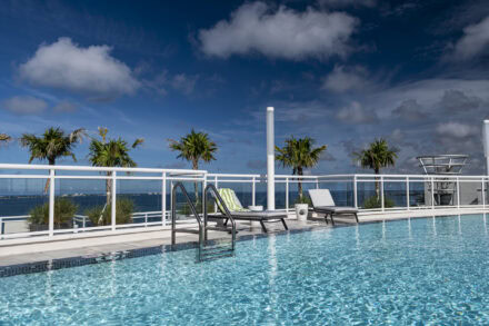 pool at sarasota's blvd condominiums with glass railing, palm trees, blue sky and bay views