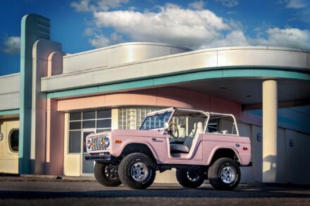 restored 1967 pink ford bronco parked in front of modern 1950's architecture