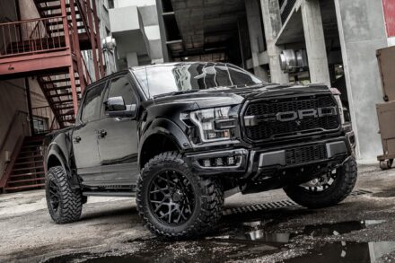 black ford raptor in alley way with concrete walls, puddles, and red stairs