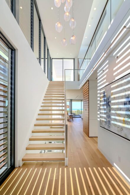 modern residential interior with floating wood staircase and glass railing