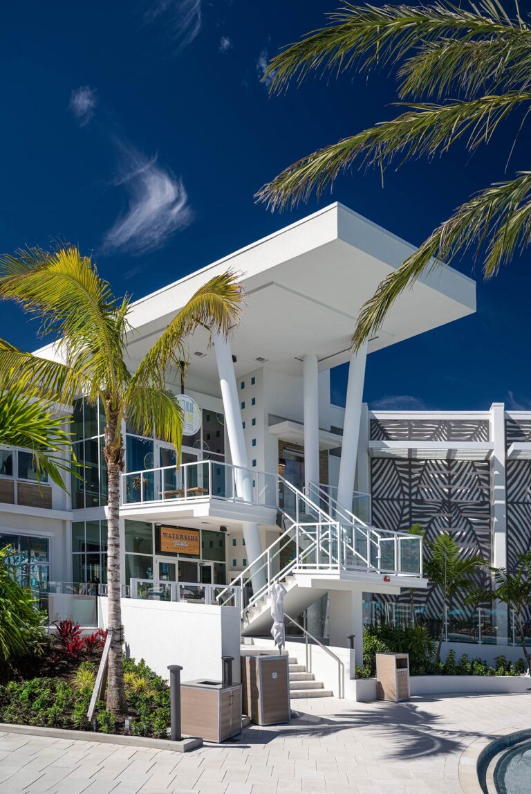 modern architecture white building with white columns, palm trees and glass stair rail