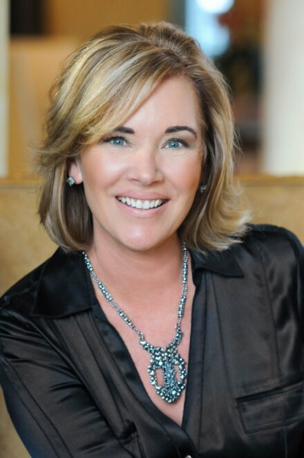 professional on-location headshot of blond woman with blue eyes and black silk blouse