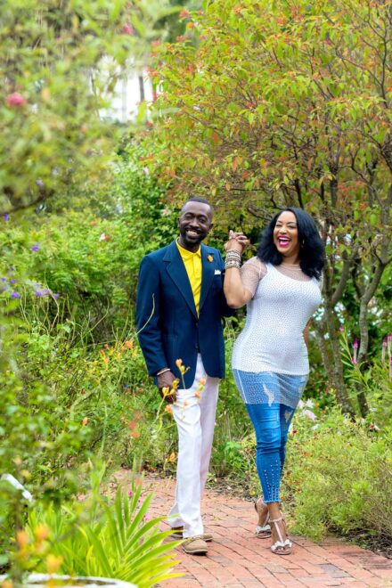 man and woman walking through garden holding hands laughing