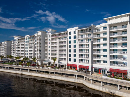aerial view of a large multilevel hotel on a body of water with aluminum balcony railing and a walkway below