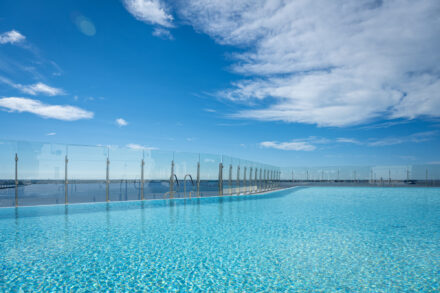 Frameless Glass Railing lining an infinity pool on the upper level of a building overlooking water