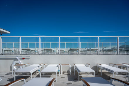 white and wood sunchairs on a deck with aluminum and glass railing