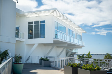 white modern building with floor to ceiling windows, glass railng and a white metal sunshade