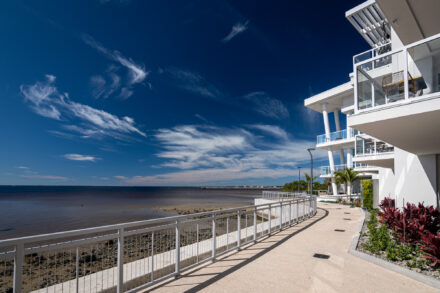 Aluminum and cable railing lining a sidewalk alongside Charlotte Harbor with modern 3 story building