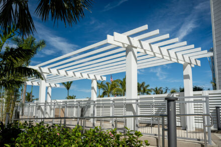 white pergola feature with louver fence to its right and aluminum and cable railing to left