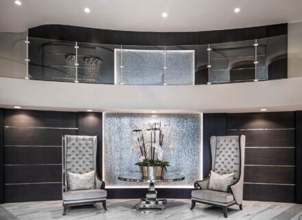interior photograph of the luxury Seaglass Bonita Bay condominium's lobby with 2 velvet wingback chairs, a large orchid, and 2nd level glass railing