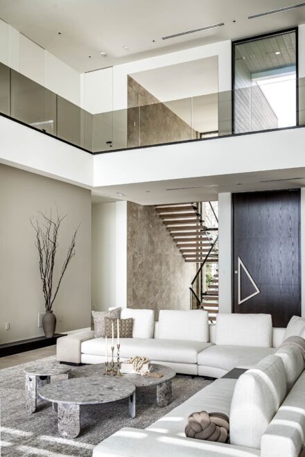 interior architectural 2 story view of a modern residence in cream and neutral tones with glass railing and floating stairs