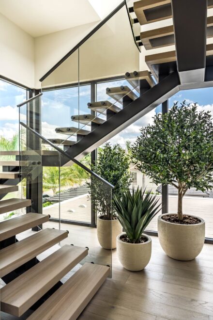 interior architectural photography of floating wood stairs, glass railing and potted plants