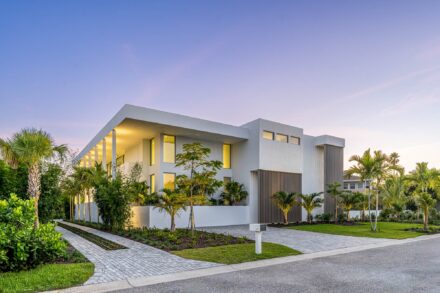 modern white geometrical residence on longboat key florida at sunset with tropical landscaping and bronze sunshades