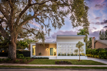 An architectural photograph of a modern residence in the Avondale Park Community Sarasota, Fl with custom breeze block and a large oak tree against a dusk sky