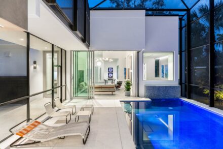 architectural photography of a modern pool deck at dusk opening to a living dining room