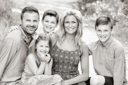 a family of parents and three children sitting together, smiling