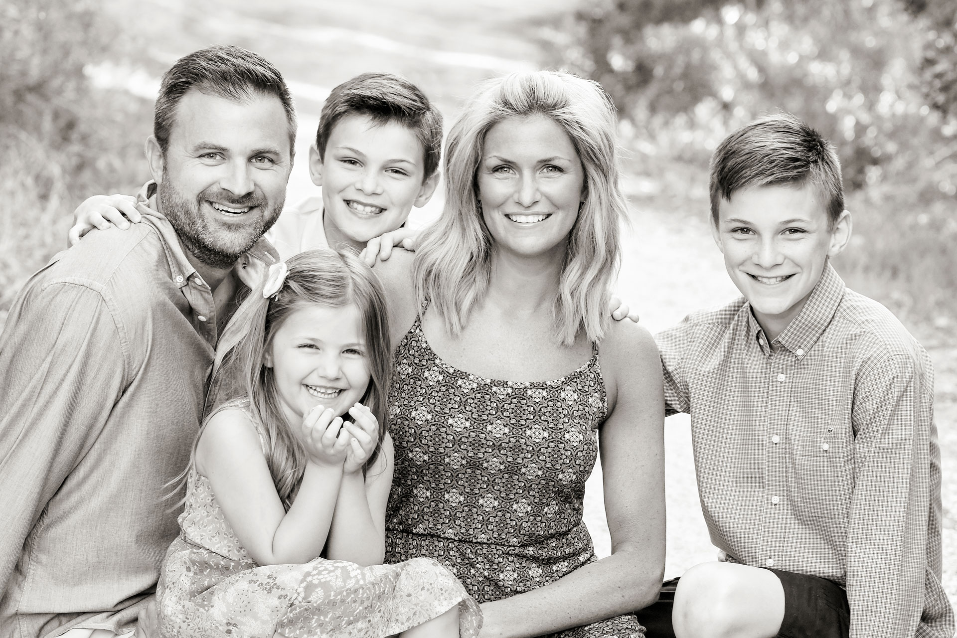 a family of parents and three children sitting together, smiling