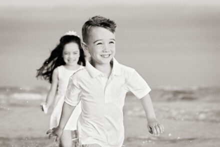 little boy and girl running and laughing on beach