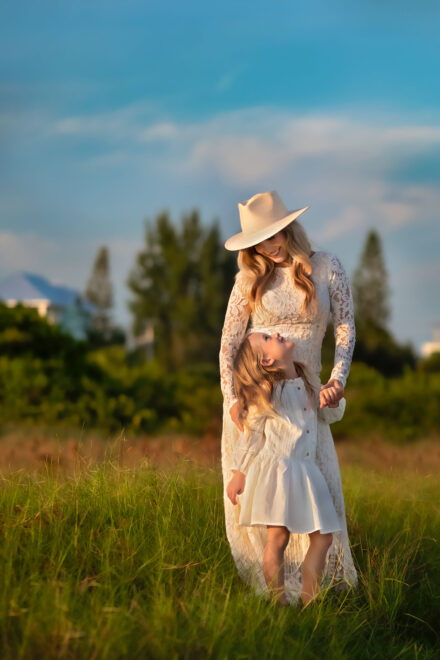 mom and daughter with white dresses on standing in Siesta Key beach sea grass looking at each other smiling holding hands