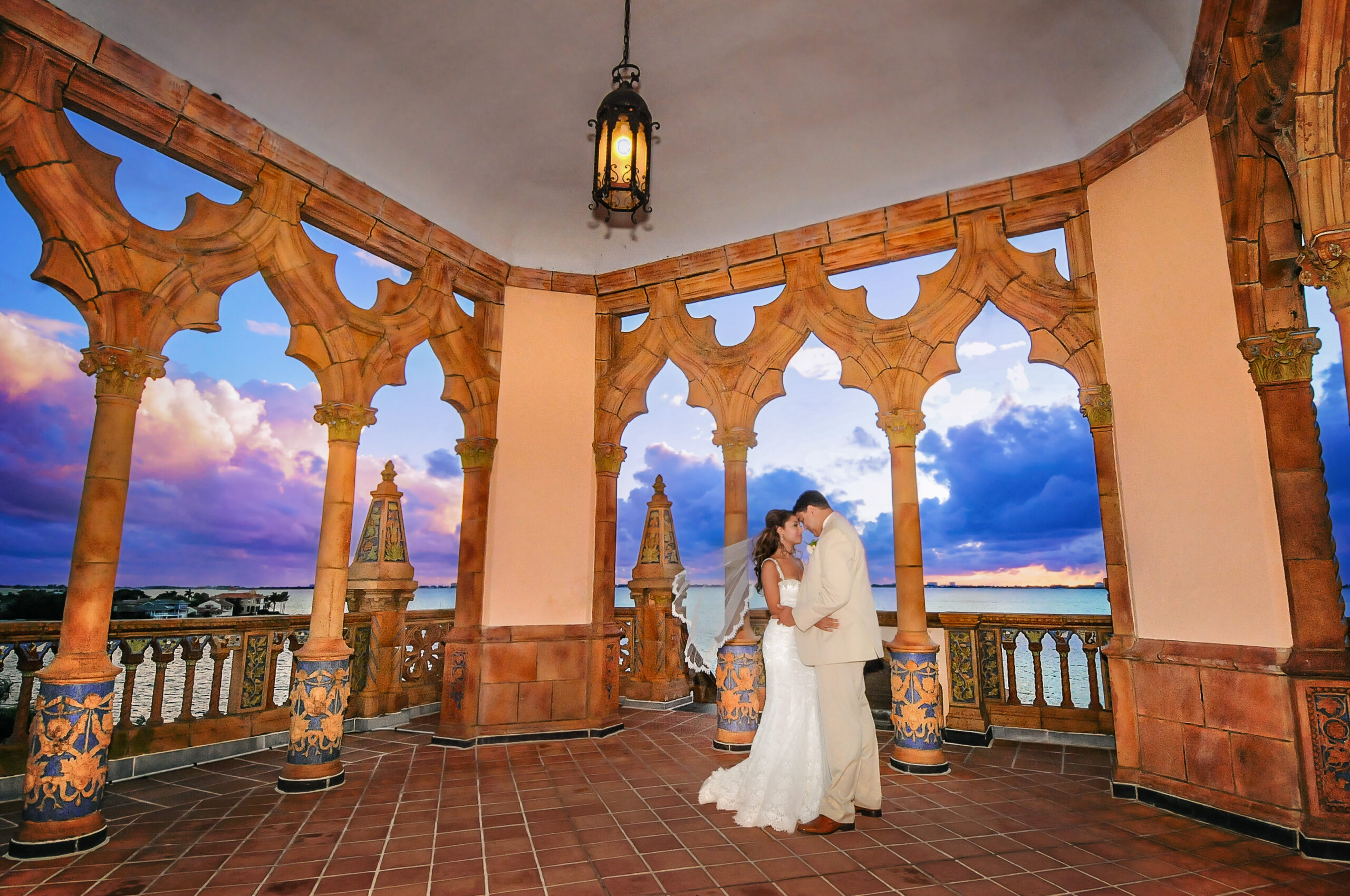 bride and groom embracing in the Ca' d'zan Belvedere Tower with a sunset background