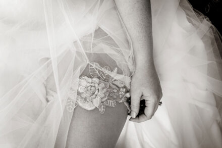 closeup of bride's garter belt, wedding dress, and hand
