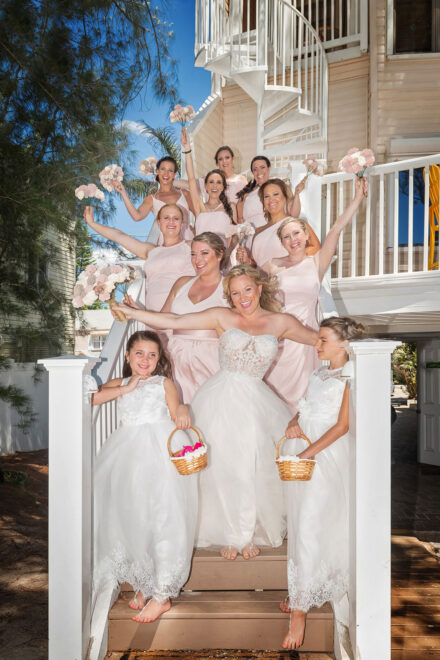 bride and bridal party laughing and cheering on staircase of beach home