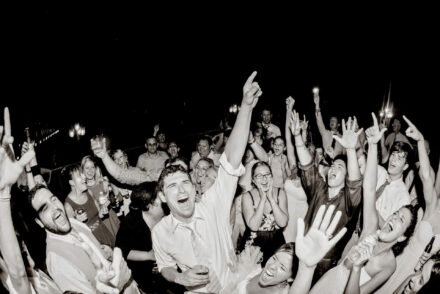 wedding reception guest dancing, raising hands, and singing
