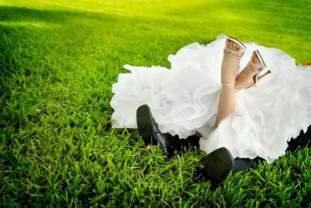 bride with white heels on lying on groom with black dress shoes on in grass at ringling museum lawn with only feet showing