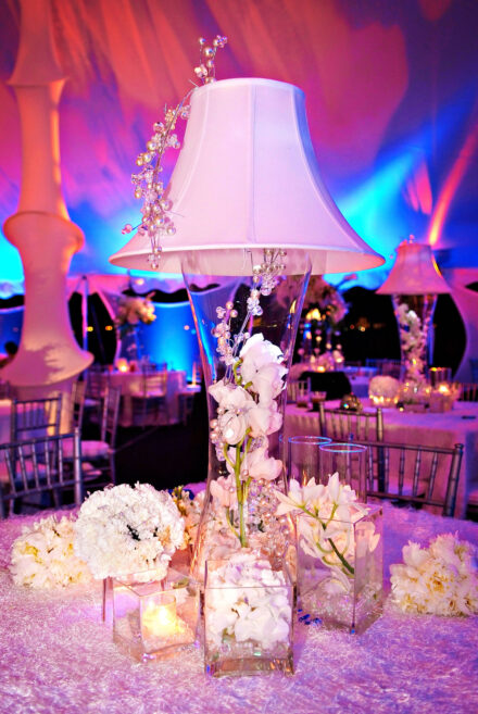 white flowers in clear square glass vases on table under colorful tent at wedding reception